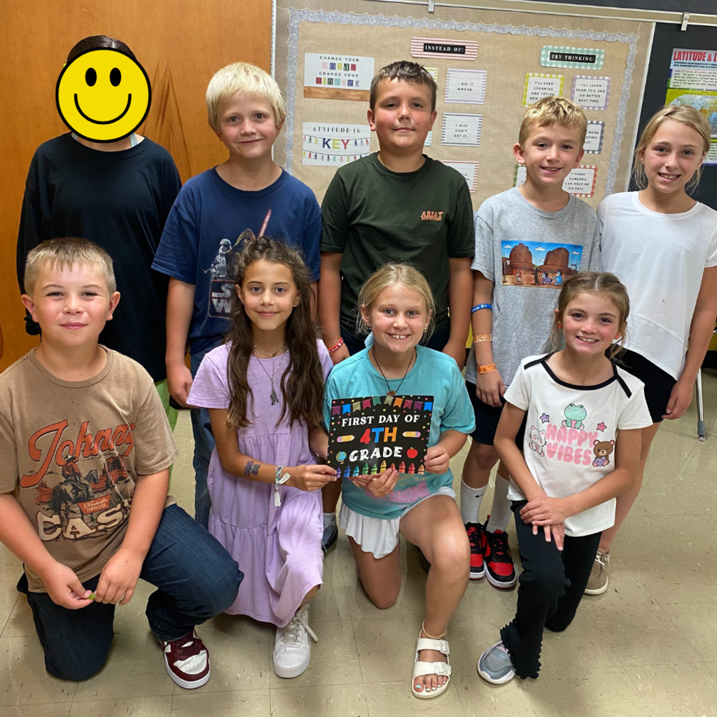 Elementary students posing with a First Day of Fourth Grade sign