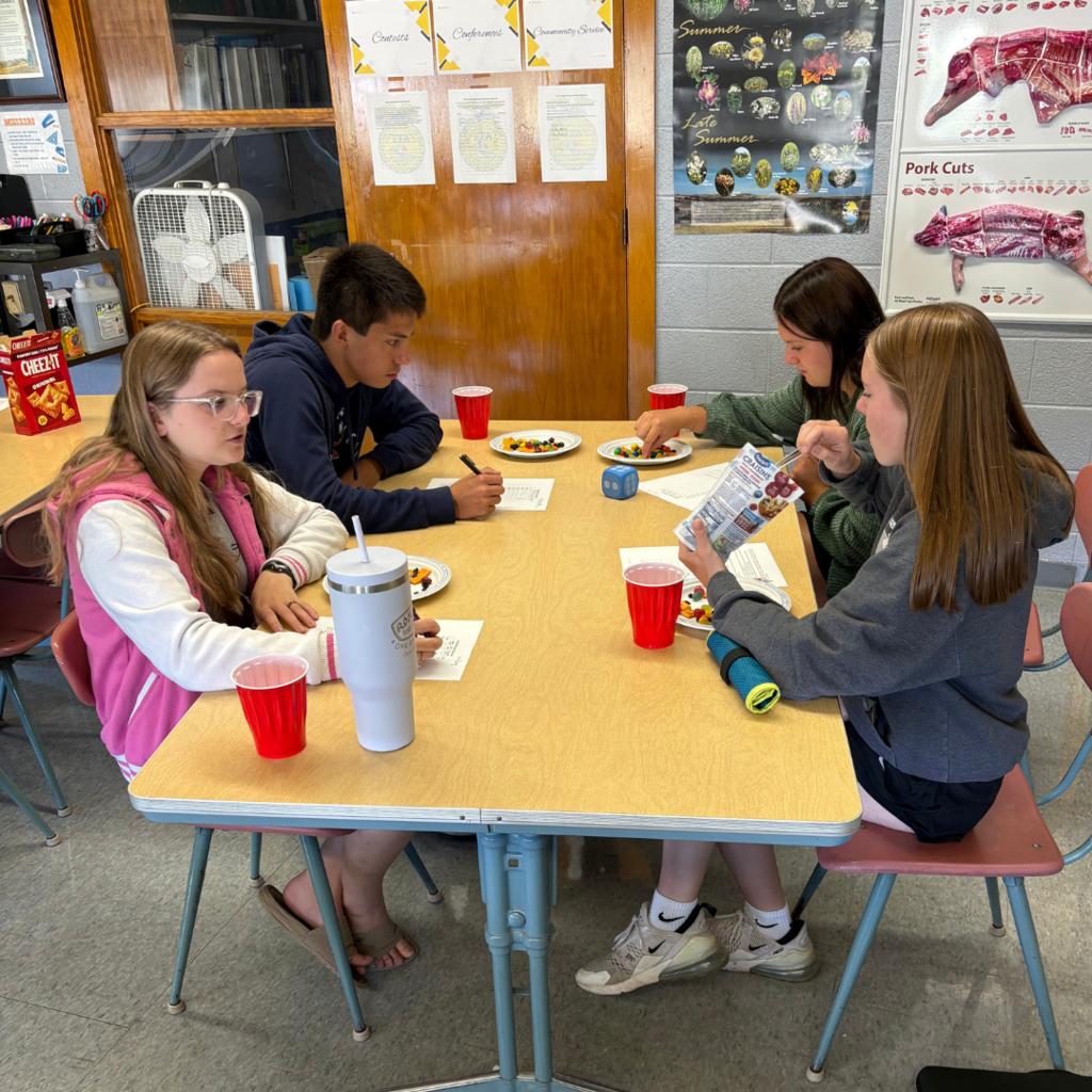 High school students sitting at a table with plates of snacks