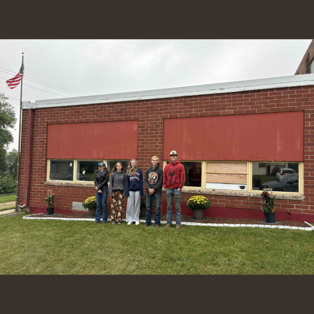 High school students posing in front of their landscaped flower garden in front of a school