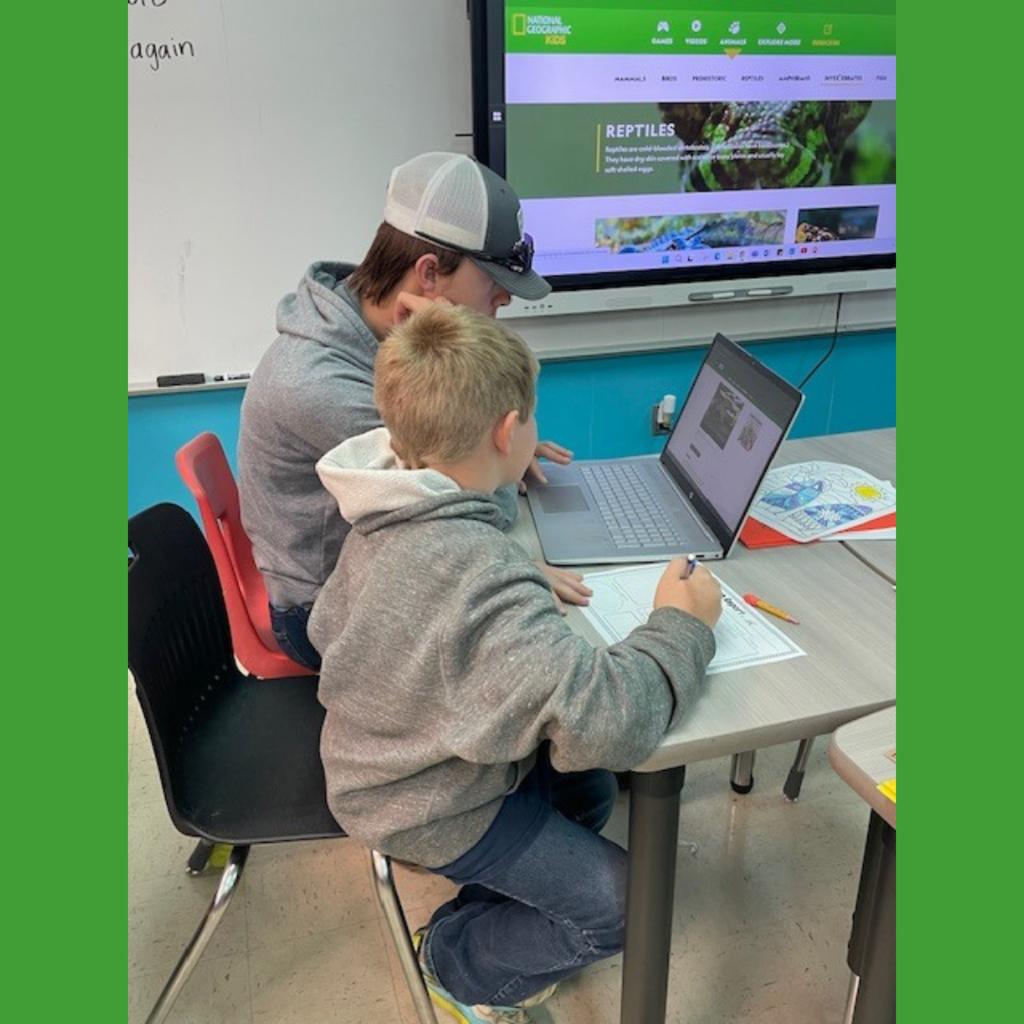 High school and elementary school students working together using laptops to conduct research