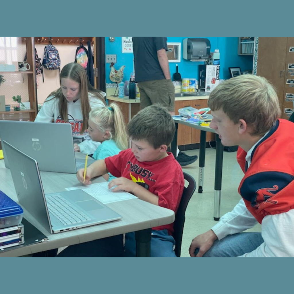 High school and elementary school students working together using laptops to conduct research