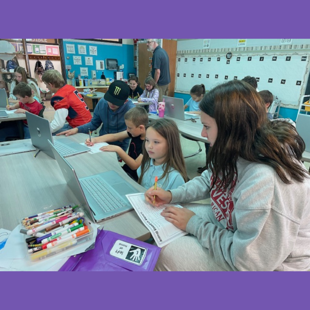 High school and elementary school students working together using laptops to conduct research