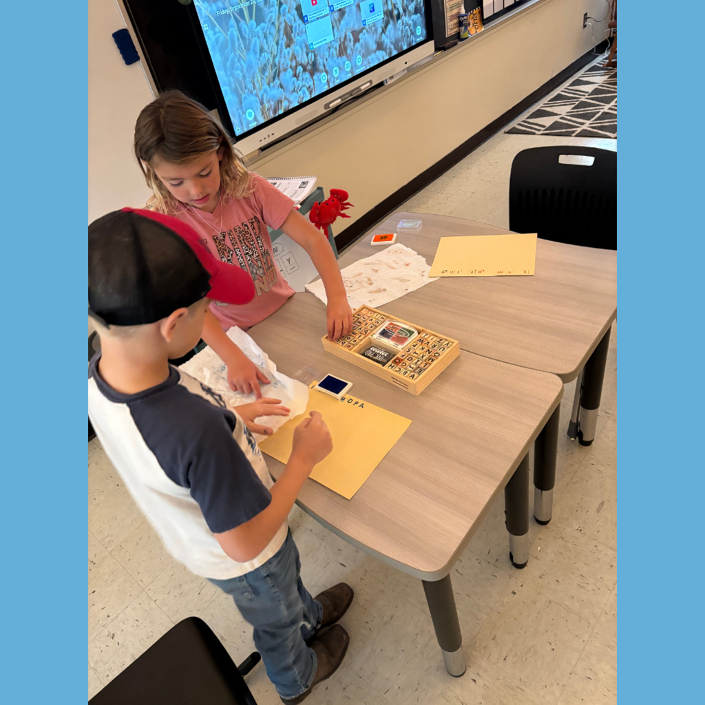 Lower elementary students using letter stamps on paper to write stories