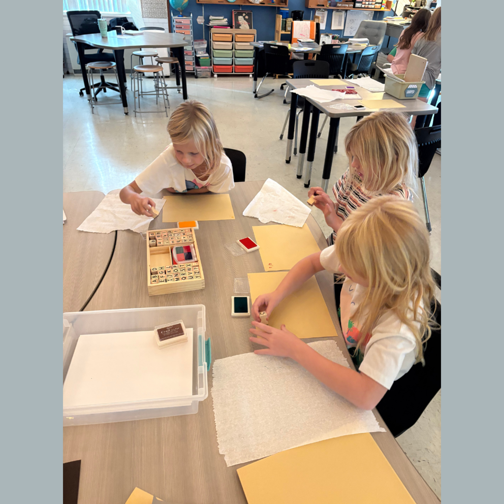 Lower elementary students using letter stamps on paper to write stories