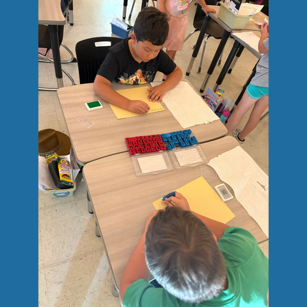 Lower elementary students using letter stamps on paper to write stories