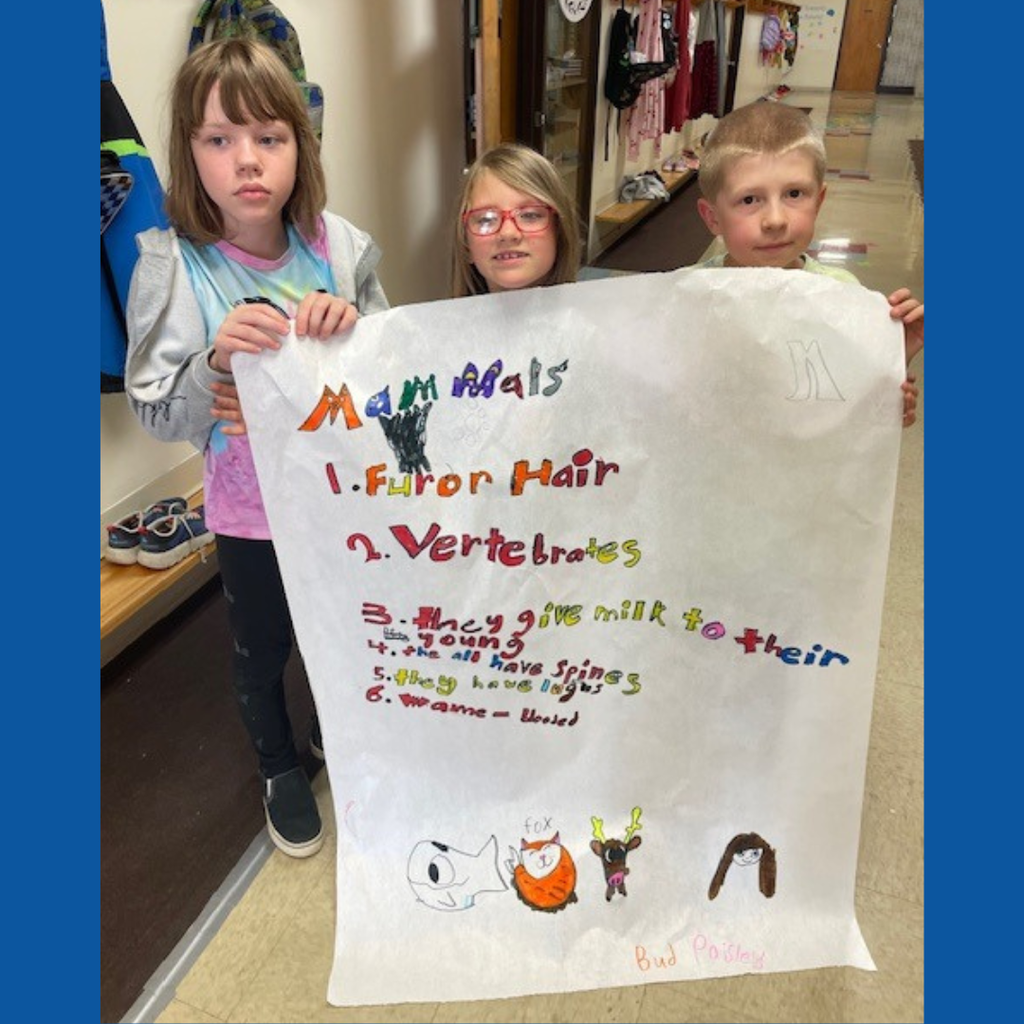 Elementary students posing with a large handmade poster