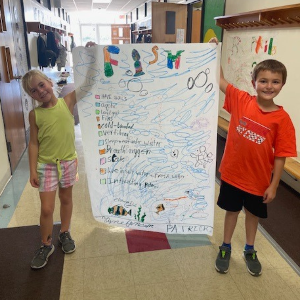 Elementary students posing with a large handmade poster