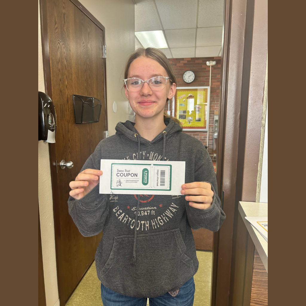 A high school girl holding a paper coupon for bonus points on an assignment