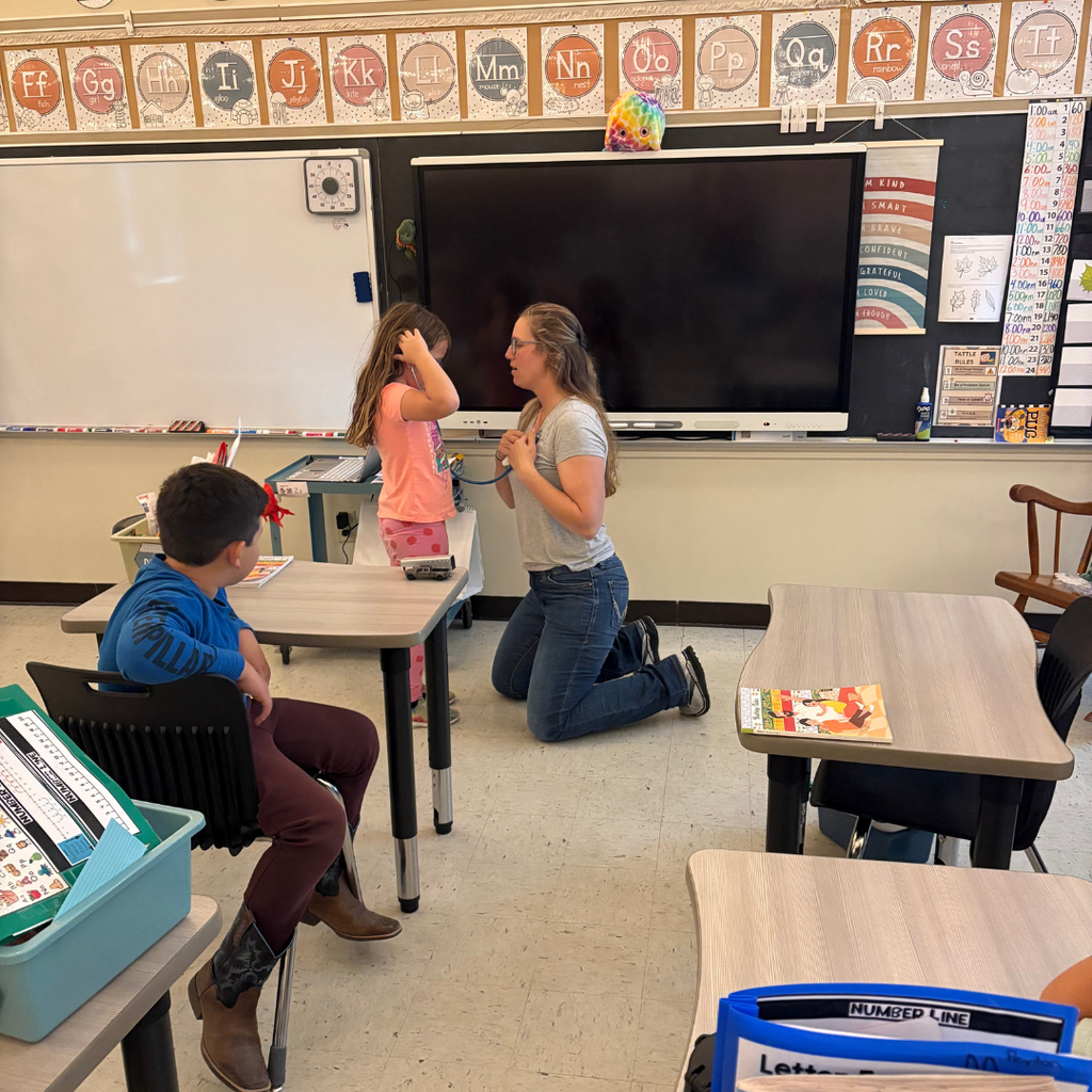 A lower elementary student using a stethoscope on a nurse