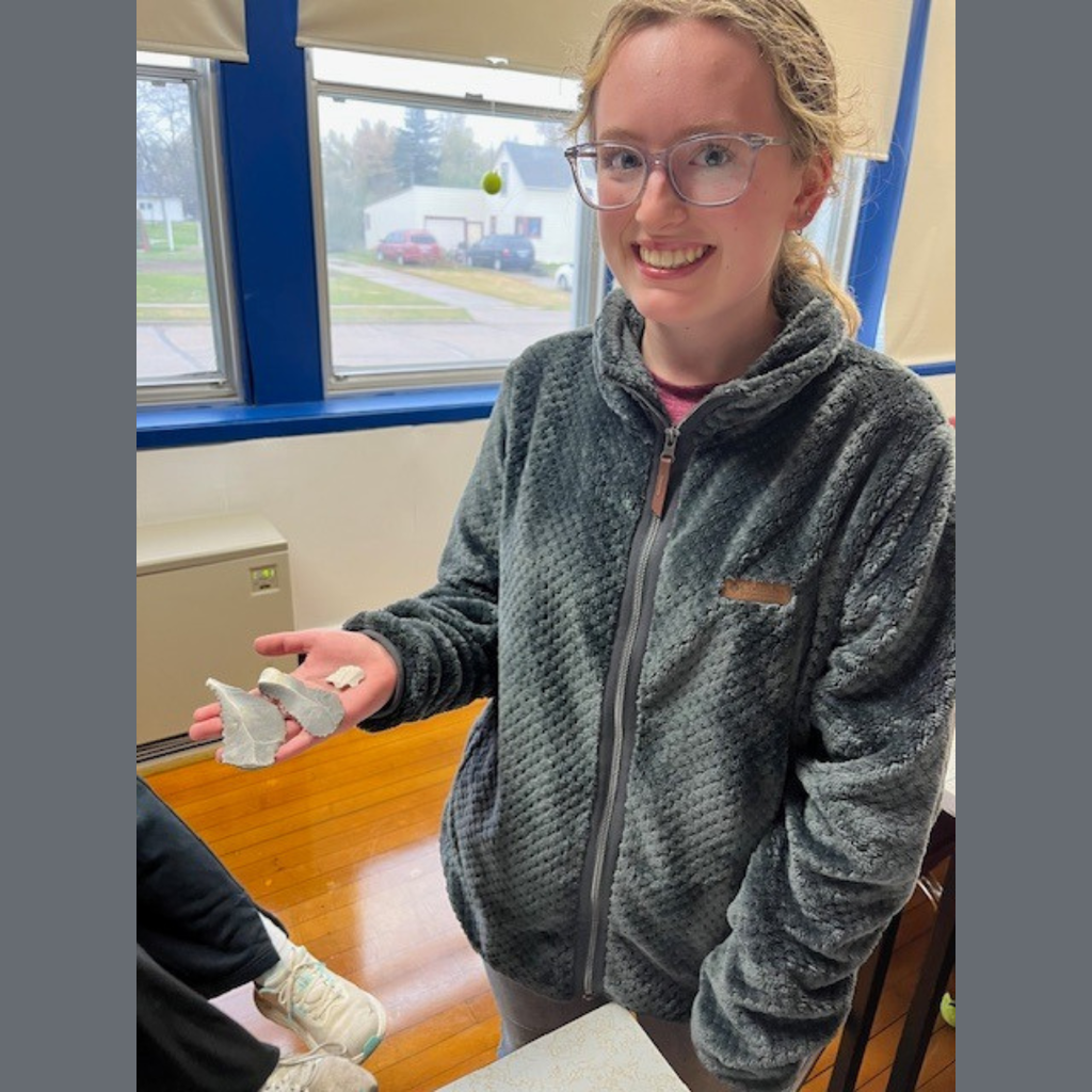A high school girl showing off her flint knapping skills.
