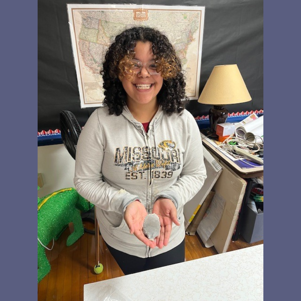 A high school girl showing off her flint knapping skills.
