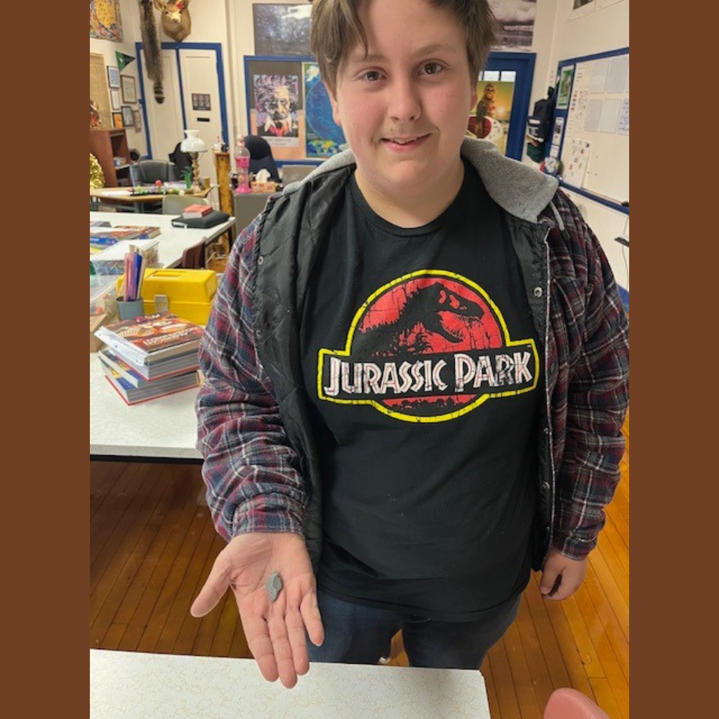 A high school boy showing off her flint knapping skills.