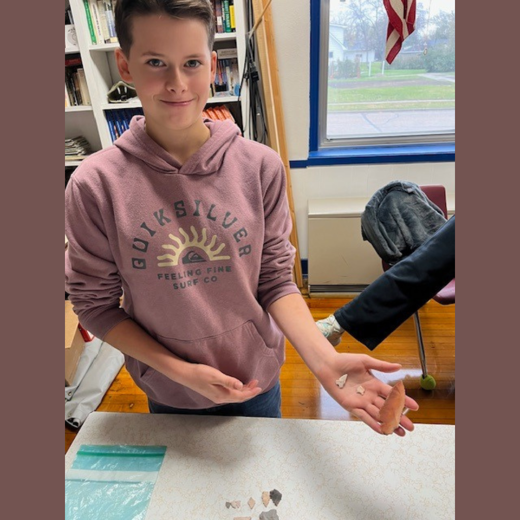 A high school girl showing off her flint knapping skills.