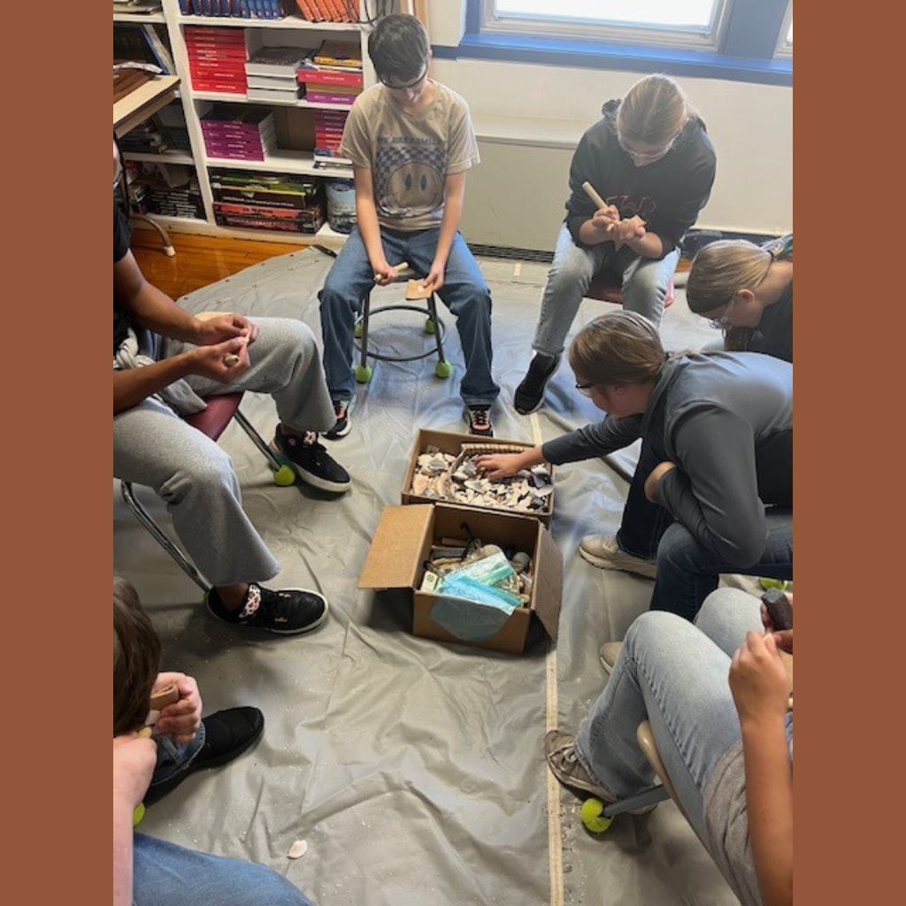 High school students gathered around a box of rocks.