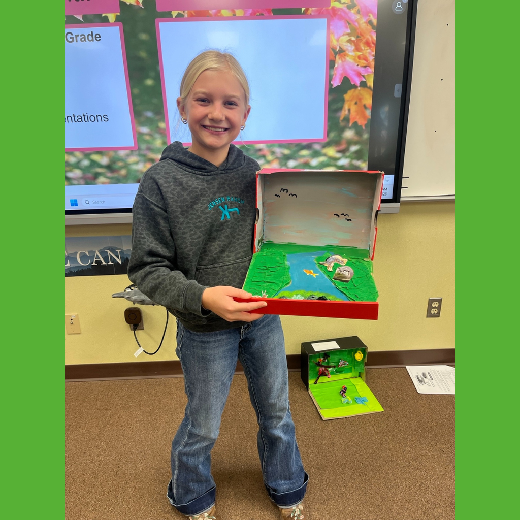 A sixth grade student showing off her homemade shoebox biome
