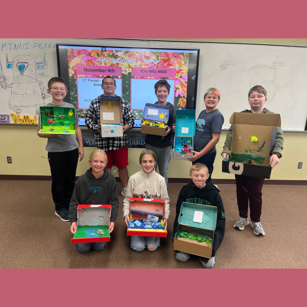 Sixth grade students posing with their homemade shoebox biomes.