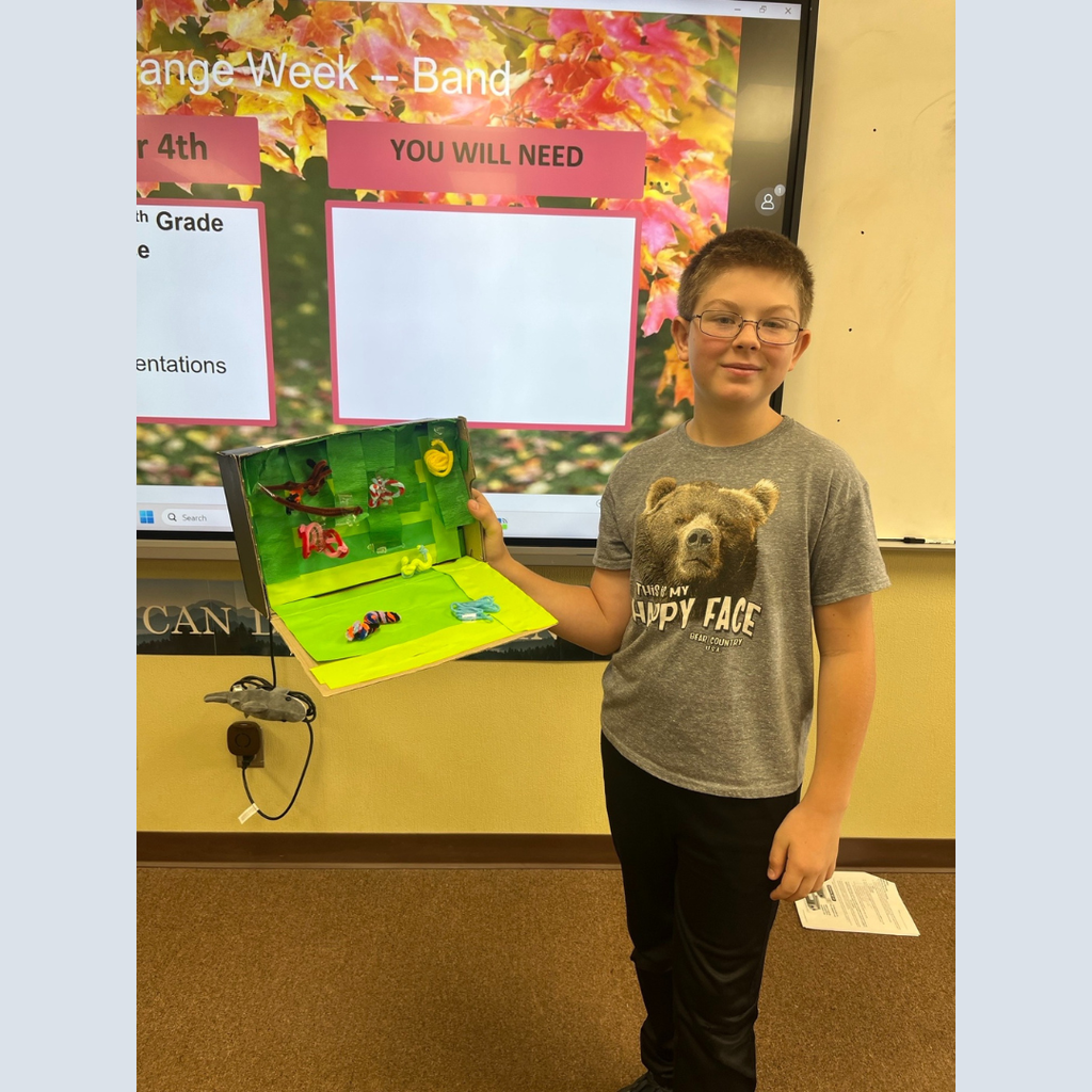 A sixth grade student showing off his homemade shoebox biome
