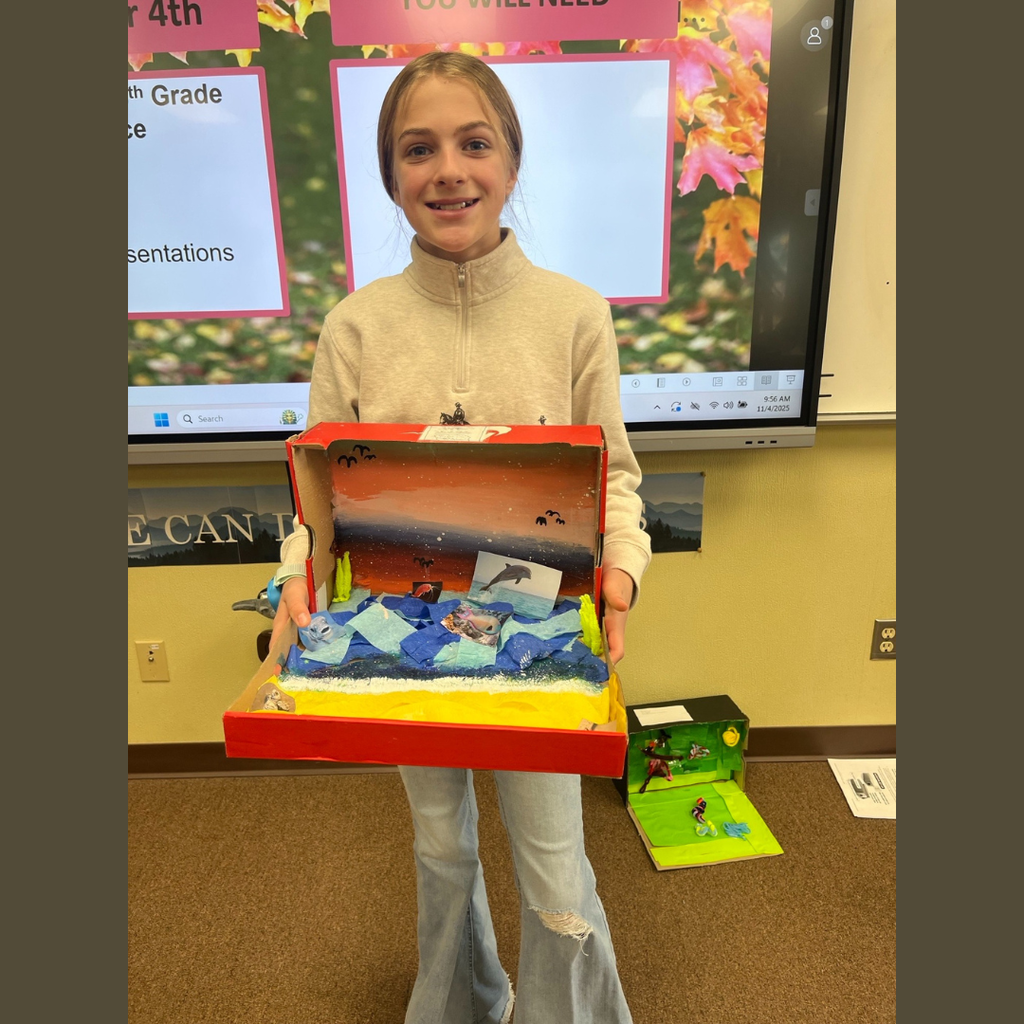 A sixth grade student showing off her homemade shoebox biome