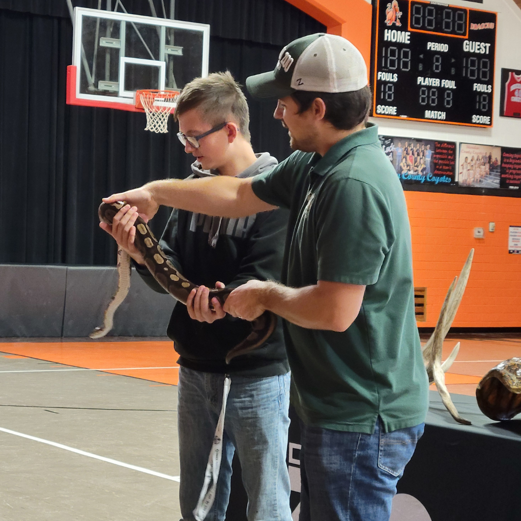 A man helping a high school student hold the python