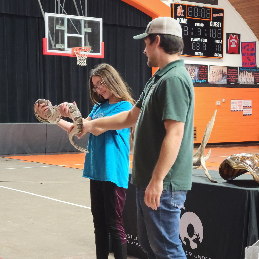 A man helping a high school student hold the python