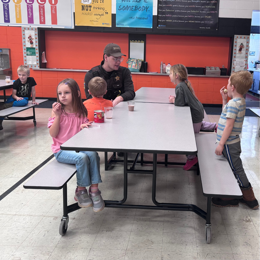 A school resource officer sitting at the lunch table with elementary students