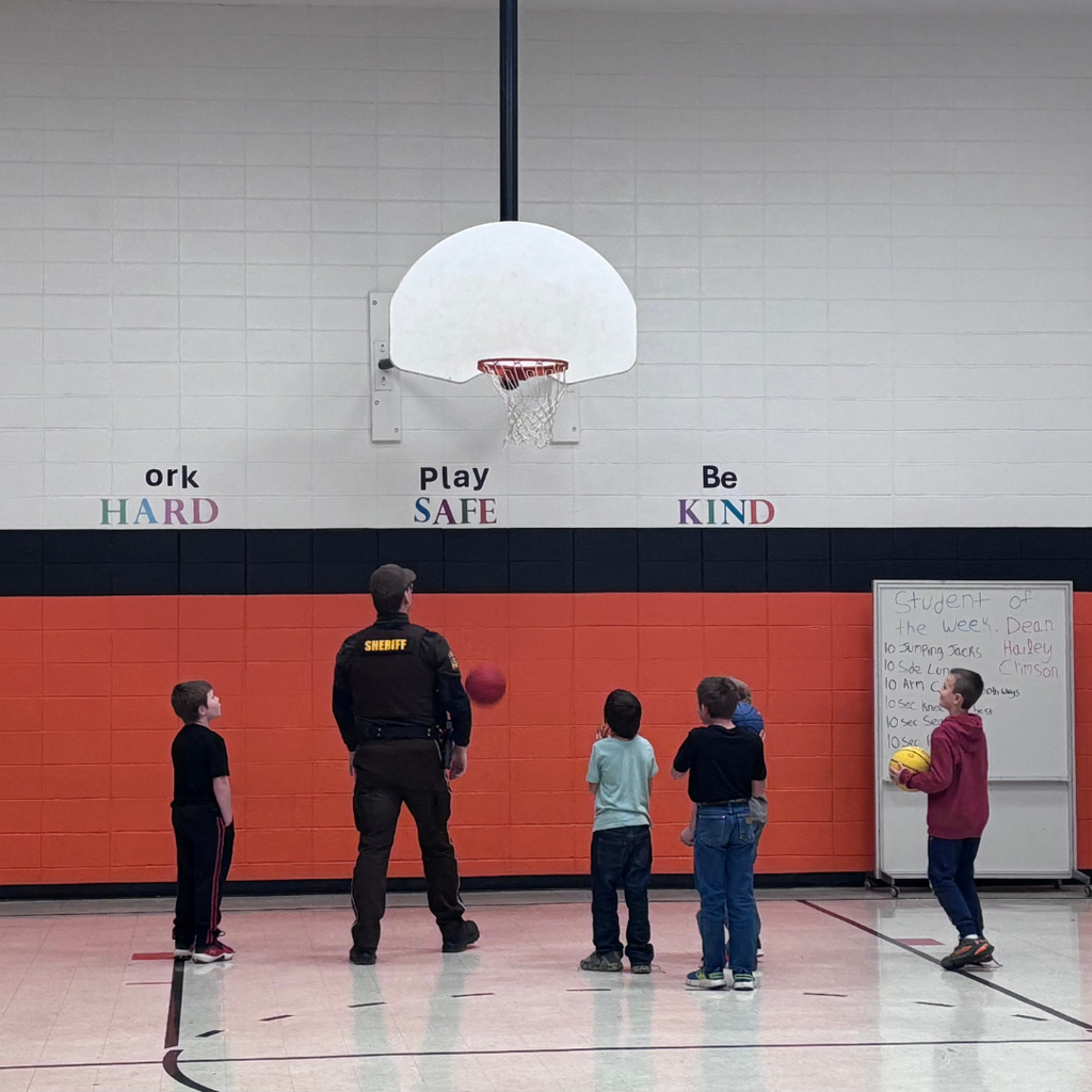 A school resource officer playing basketball with elementary students