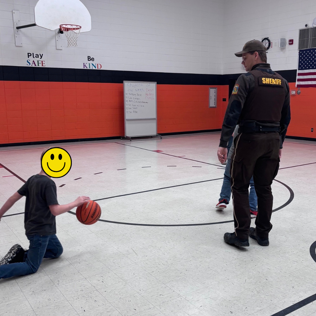 A school resource officer playing basketball with elementary students