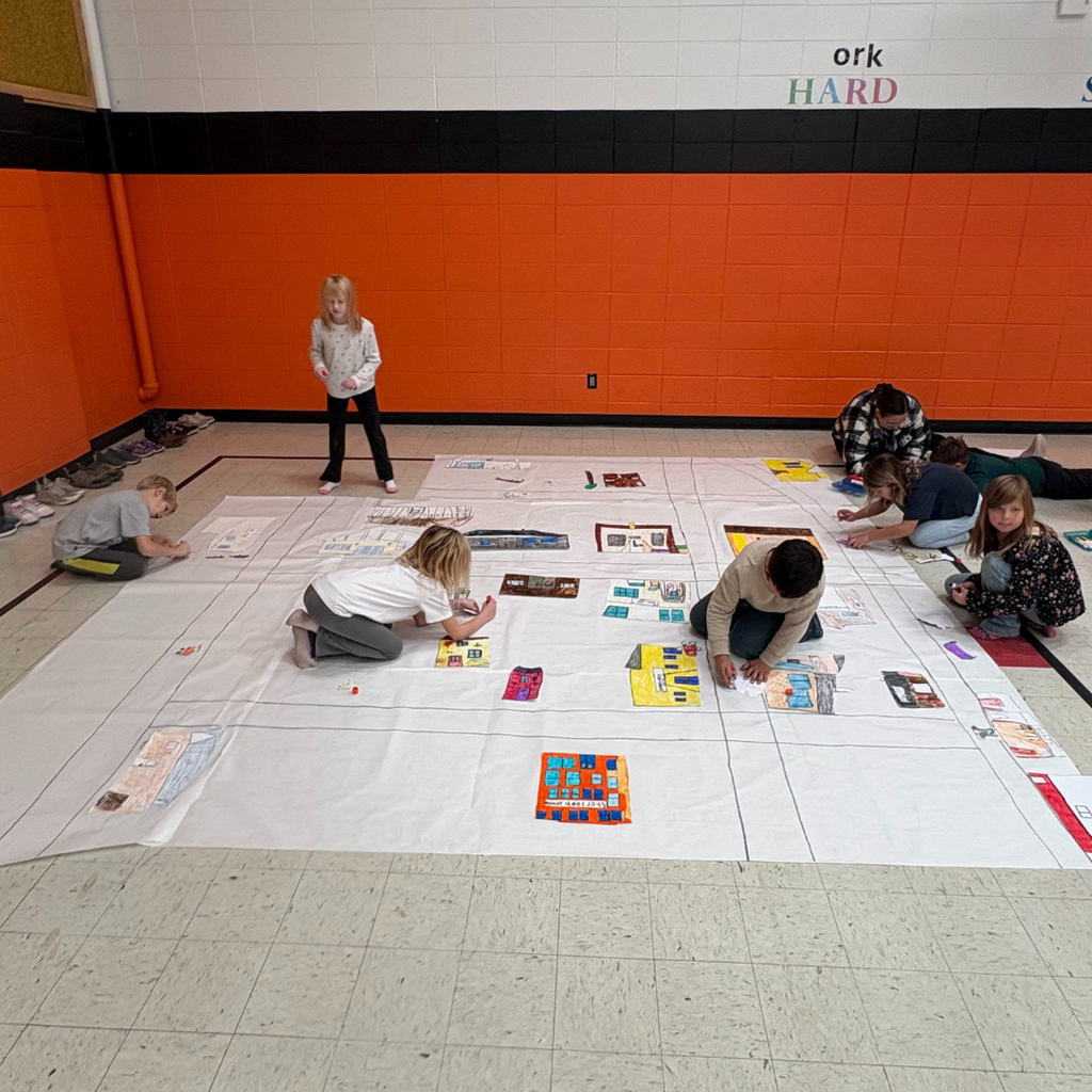 Lower elementary students drawing buildings on a large poster