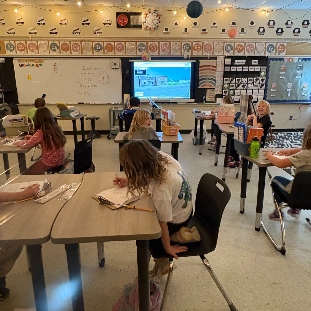 Lower elementary students watching a lesson on a smartboard