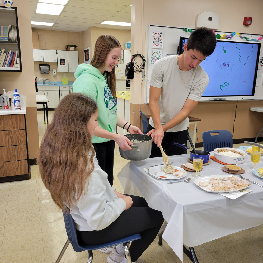 Two high school students serving Thanksgiving dinner to their classmates