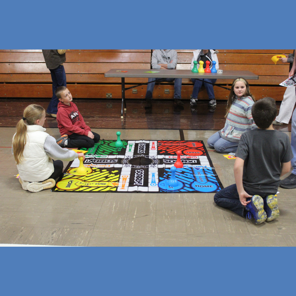 Four elementary students playing with a giant Sorry board