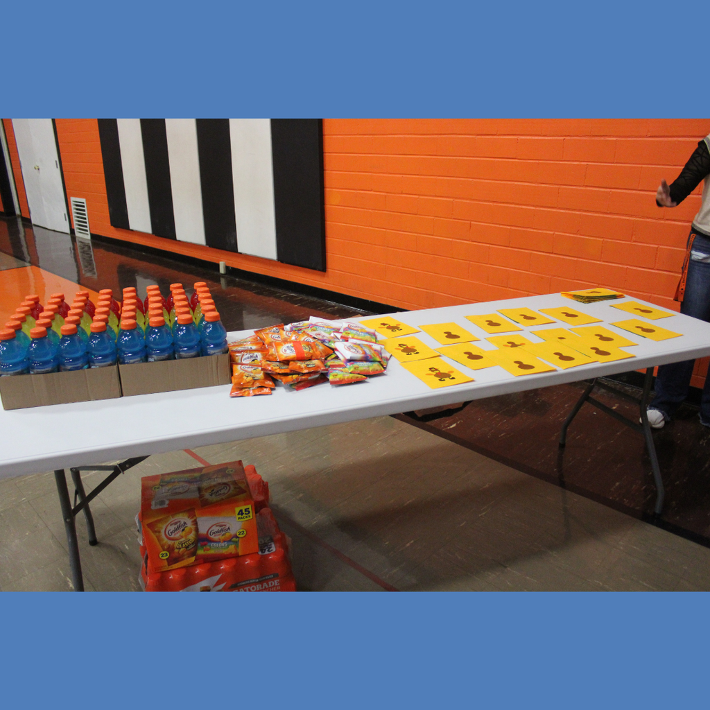A table filled with Gatorade bottles, small bags of Goldfish crackers and pieces of paper with turkey stickers