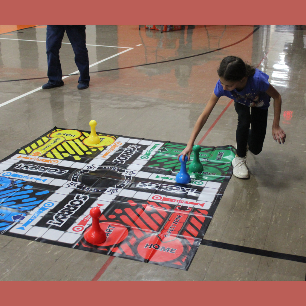 An elementary student playing with a giant Sorry game board
