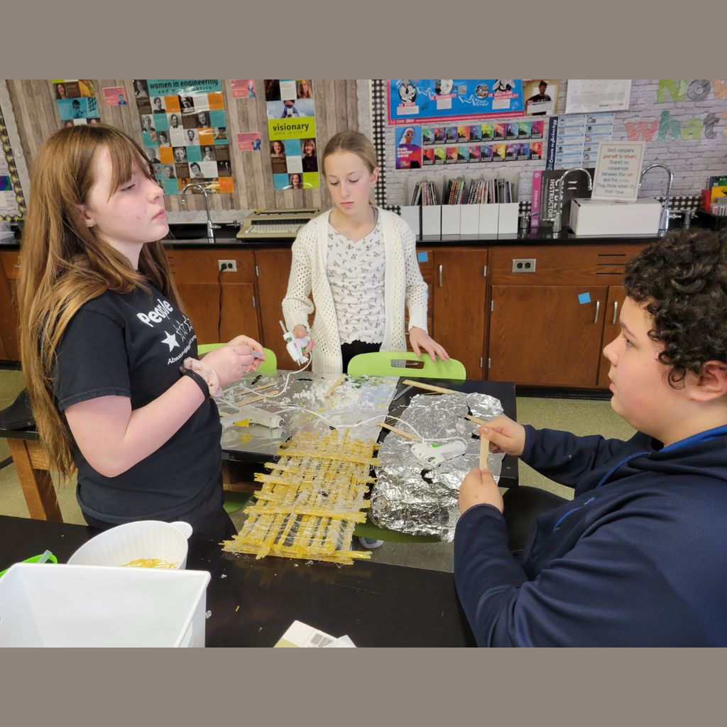 Junior high students building a bridge out of dry spaghetti noodles and hot glue