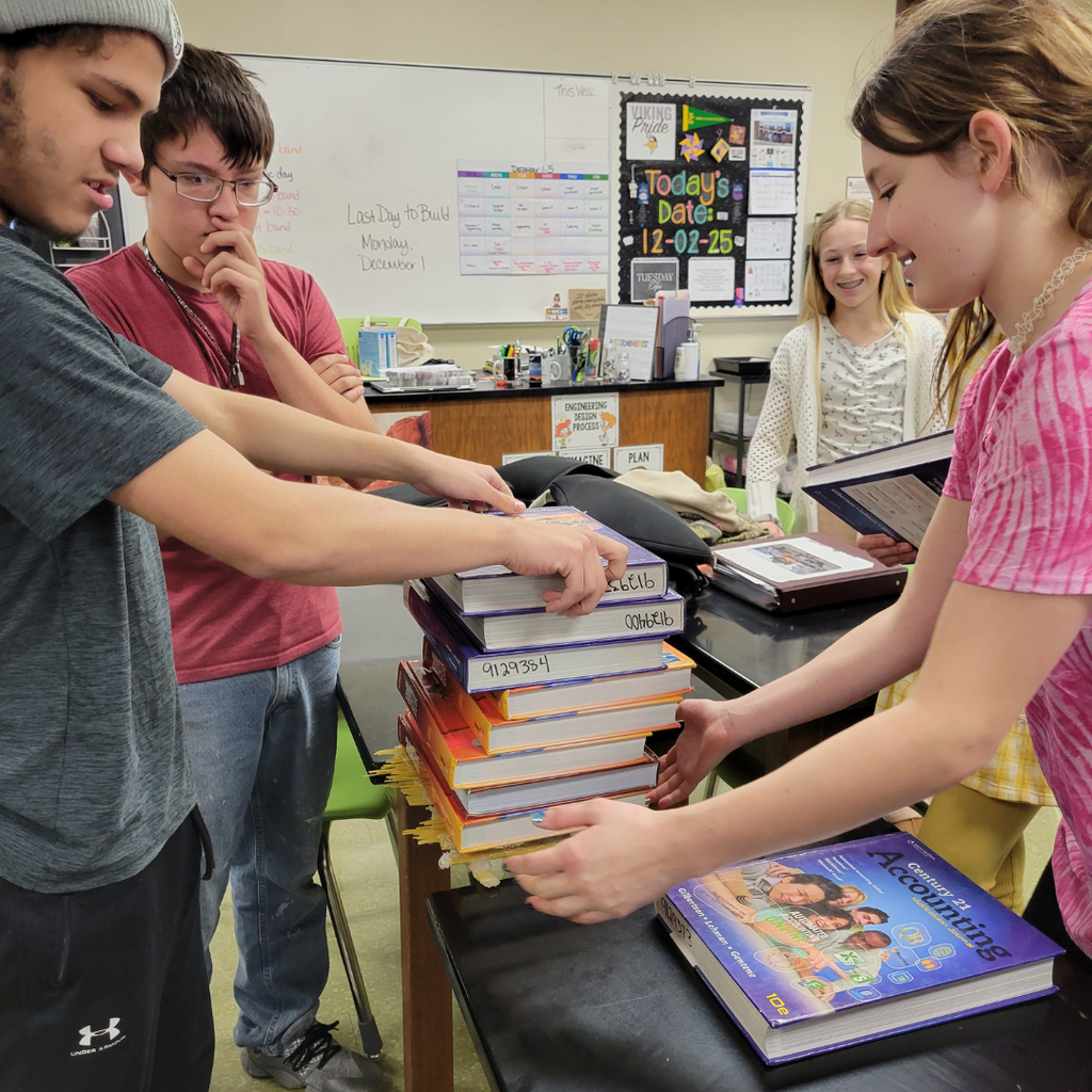 Junior high students stacking textbooks on top of their spaghetti bridge
