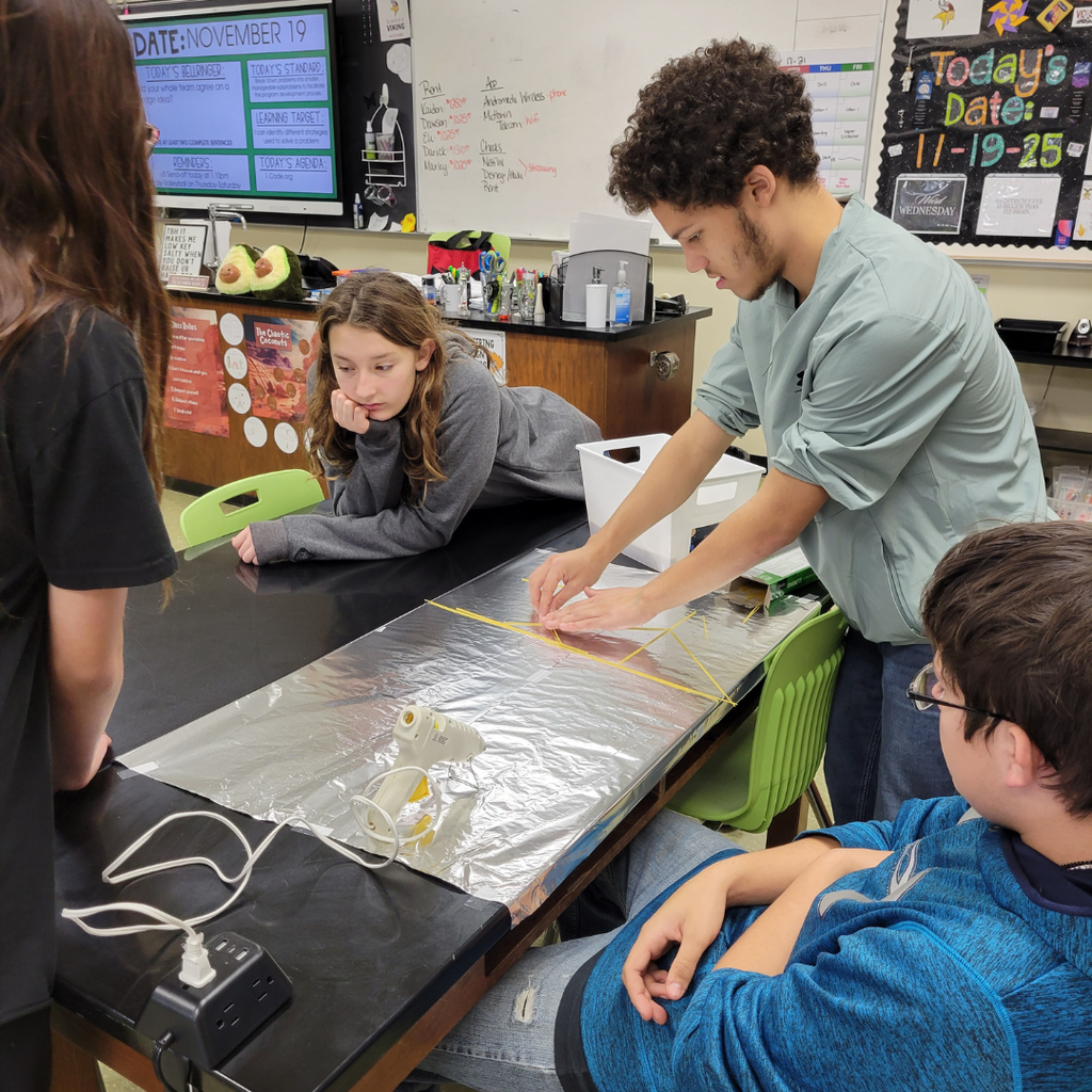 Junior high students building a bridge out of dry spaghetti noodles and hot glue