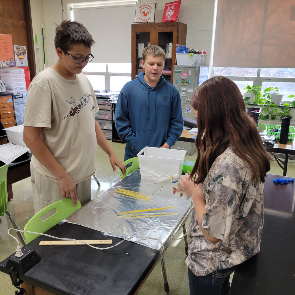 Junior high students building a bridge out of dry spaghetti noodles and hot glue