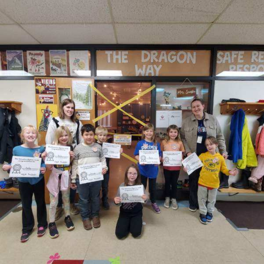 Elementary students and their teachers posing with paper certificates