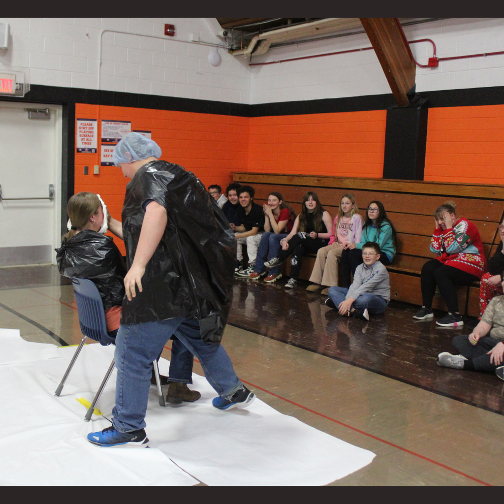 A student pies another in the face while younger students watch