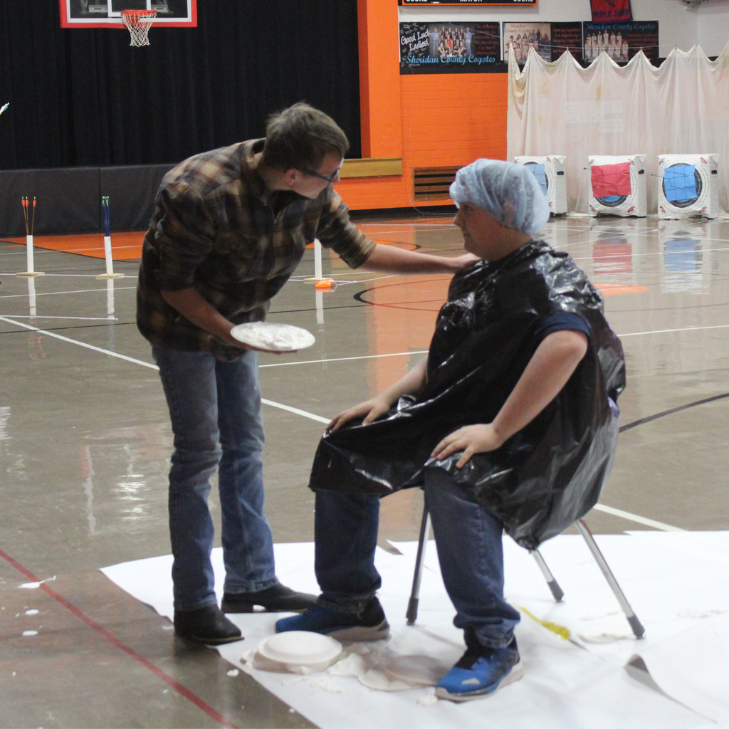 A high school student getting ready to pie another in the face