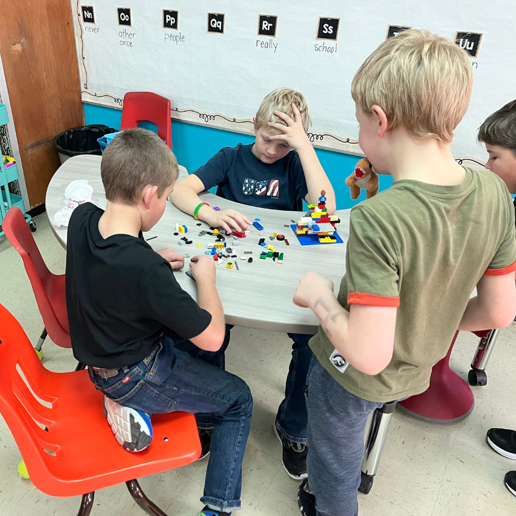 Elementary students sitting around a table playing with Lego