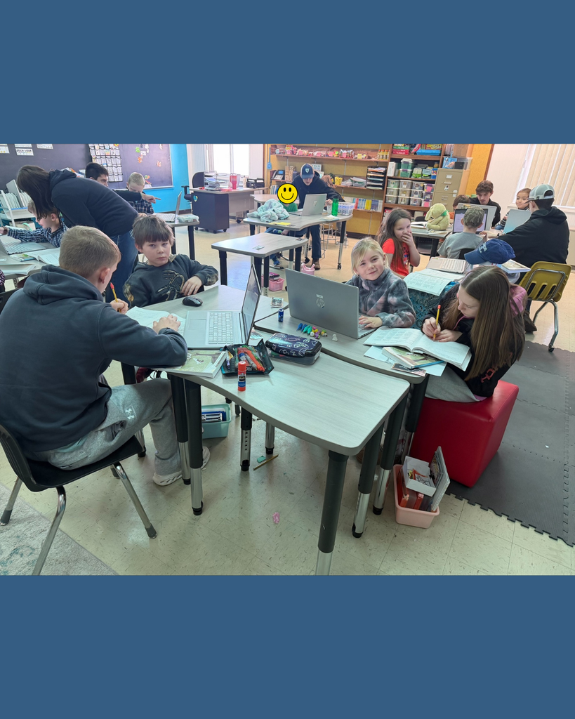 Elementary students and their high school mentors conducting research on their computers.