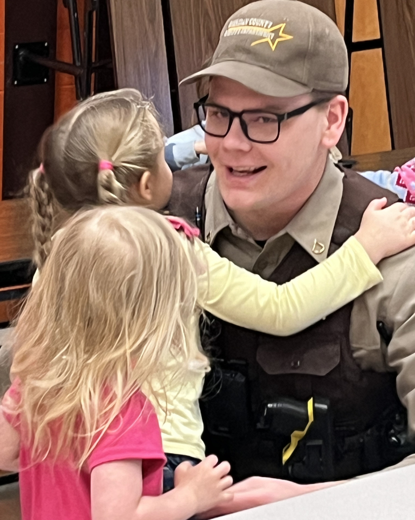 A male school resource officer getting hugs from lower elementary girls