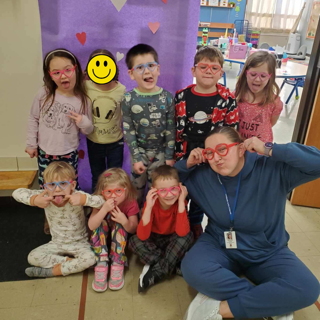 Preschool students wearing heart-shaped glasses and posing with their teacher