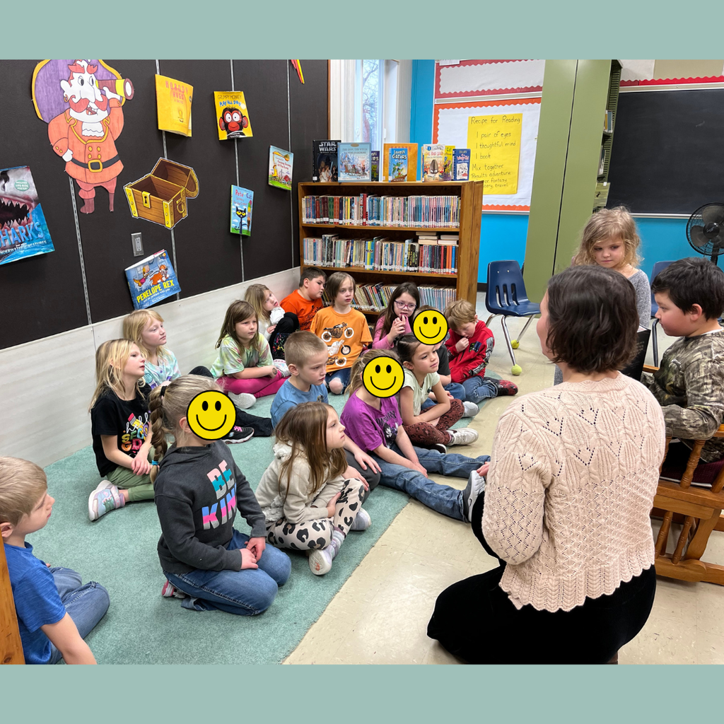 Elementary students gathered around an adult author reading her book