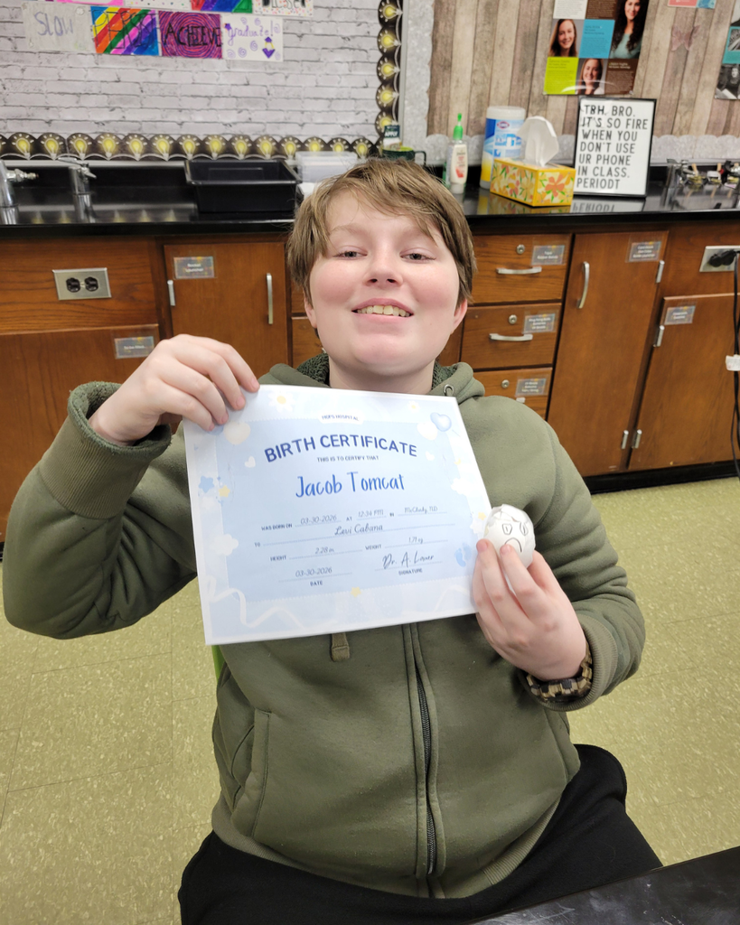 A junior high student holding an egg and a birth certificate