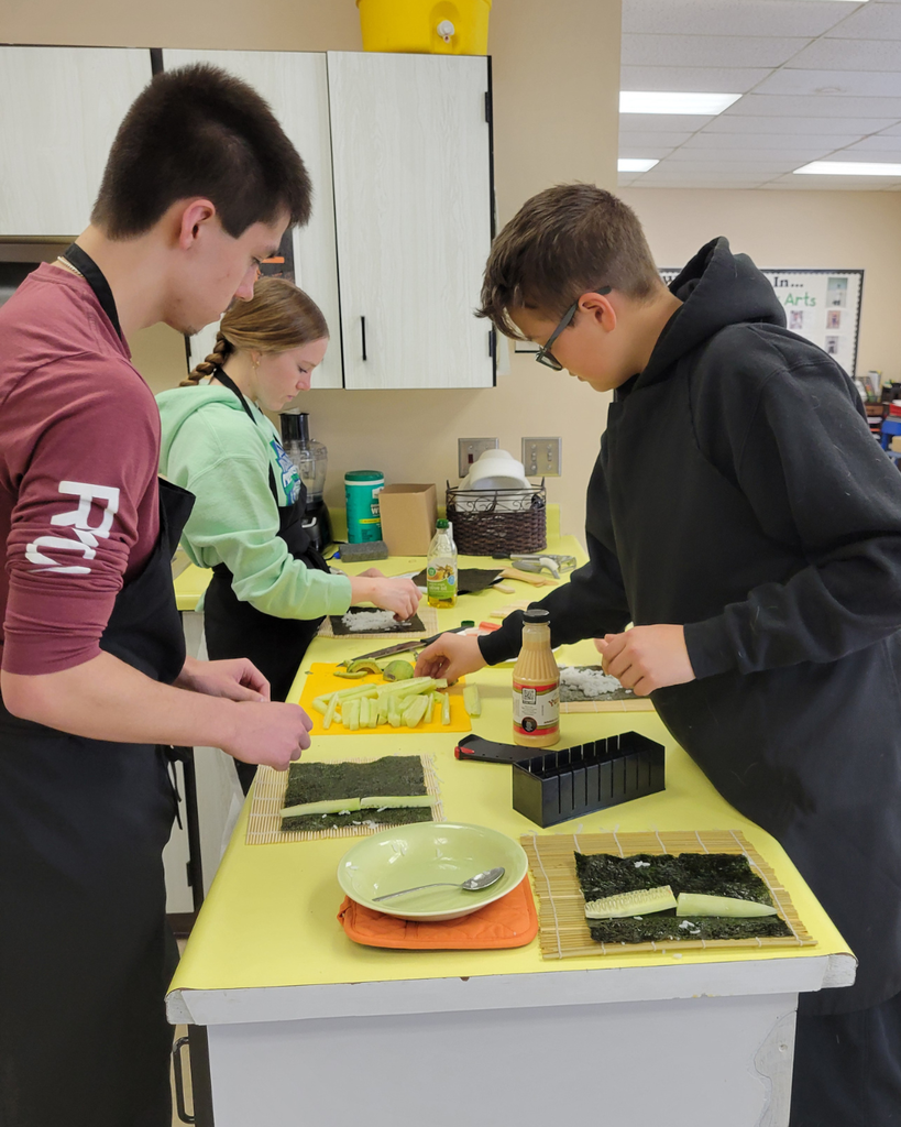 Two high school students making sushi in a kitchen setting