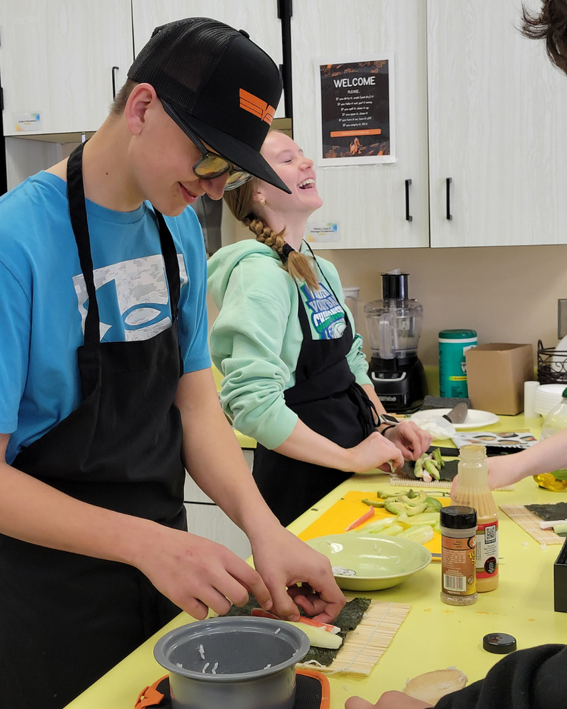 Two high school students making sushi in a kitchen setting