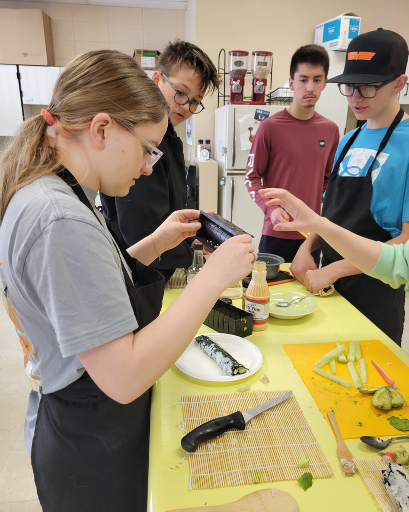 Four high school students making sushi in a kitchen setting