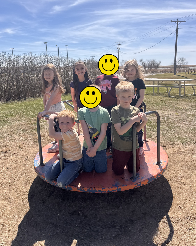 Seven kindergarten students posing on a merry-go-round